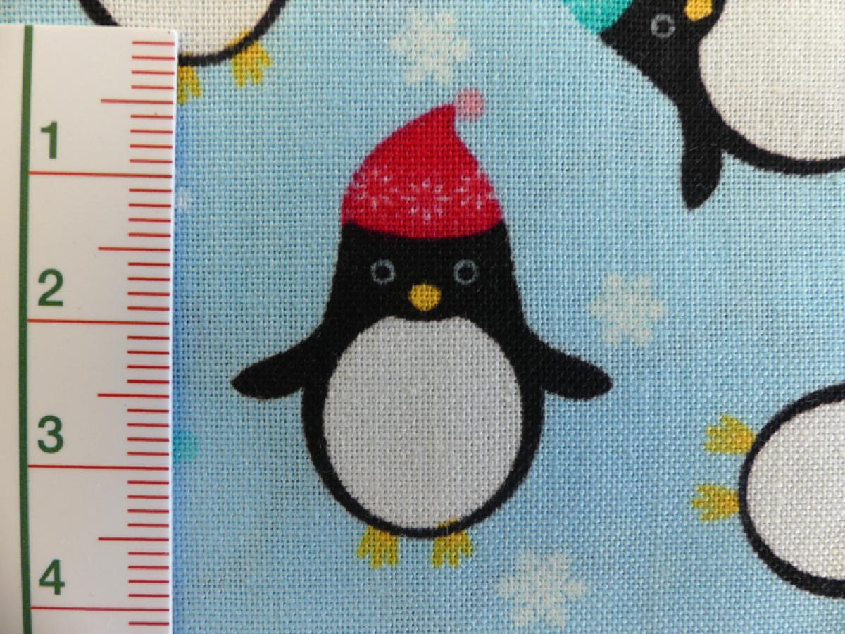 Patchworkstoff Pinguine mit Mütze auf helltürkis. Von Timeless Treasures. Detailansicht.